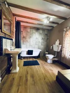 uma casa de banho com uma banheira, um WC e um lavatório. em The Raddle Inn Log Cabins em Croxden