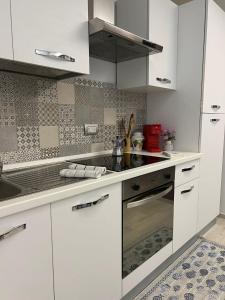La cuisine est équipée de placards blancs et d'un four avec plaques de cuisson. dans l'établissement Appartamento Melissa, à Porto SantʼElpidio