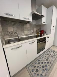 - une cuisine avec des placards blancs, un évier et un tapis dans l'établissement Appartamento Melissa, à Porto SantʼElpidio