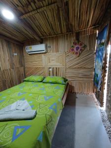 a bedroom with a green bed in a wooden room at Del Mar Vendra in Manaure Viejo
