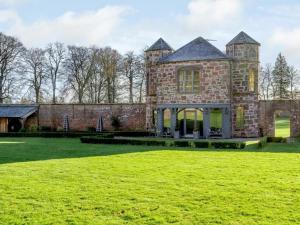 a large brick building with a grass field in front of it at The Garden Rooms in Fettercairn