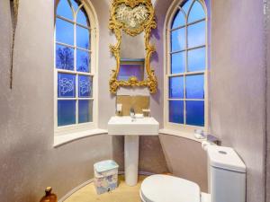 a bathroom with a toilet and a sink and windows at The Garden Rooms in Fettercairn