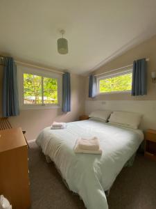 una camera da letto con un grande letto bianco con due asciugamani di Baillie Chalet on Reelig Estate Near Inverness a Kirkhill