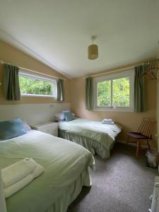 two beds in a room with two windows at Baillie Chalet on Reelig Estate Near Inverness in Kirkhill