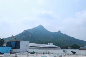 a large building with a mountain in the background at Ananda Residency in Tiruvannāmalai