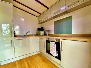 a kitchen with white cabinets and a sink at The Raddle Inn Log Cabins in Croxden