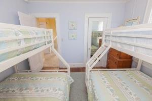two bunk beds in a room with a hallway at Shoreline Cottage - Oceanfront - North End VB in Virginia Beach