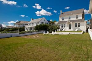 a house with a yard with white chairs in it at Shoreline Cottage - Oceanfront - North End VB in Virginia Beach
