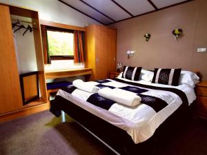 CroxdenThe Raddle Inn Log Cabins的一间卧室,有一张大床,上面有枕头