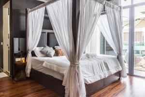 1 dormitorio con cama con dosel y cortinas blancas en Varnen Cozy Haven, en Bukit Mertajam