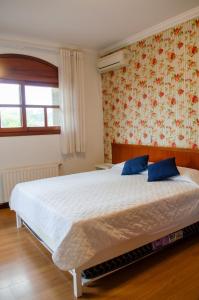 ein Schlafzimmer mit einem großen weißen Bett mit blauen Kissen in der Unterkunft Suítes Casa Aurora in Canela