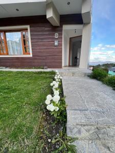 Ein Haus mit einem Haufen Blumen im Gras in der Unterkunft Ushuaia_aparts Depto 1 in Ushuaia