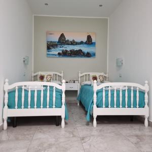 2 letti bianchi in una camera da letto con un dipinto sul muro di Al Punto Giusto a Catania