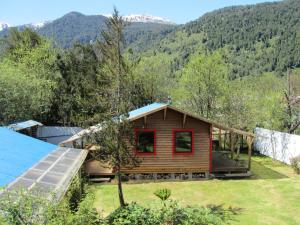 uma cabana na floresta com montanhas ao fundo em Cabañas Turin em Puerto Puyuhuapi