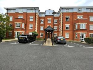 um grande edifício de tijolos com dois carros estacionados num parque de estacionamento em Spacious Apartment Near Birmingham Centre and NeC em Birmingham