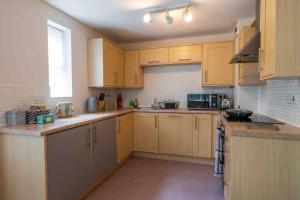 a large kitchen with wooden cabinets and appliances at Spacious Apartment Near Birmingham Centre and NeC in Birmingham