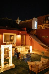 two people sitting in chairs in front of a house at night at Tuya Abu Simbel Hotel in Abu Simbel