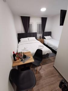 1 dormitorio con 2 camas, mesa y sillas en Golijski Biseri, en Novi Pazar