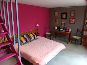 a bedroom with a pink wall and a bed at LA BARAQUE in Courtois-sur-Yonne