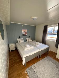 a bedroom with two beds and two windows at Lofoten Rorbuer in Svolvær