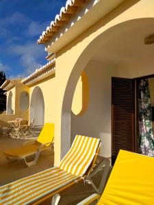 um pátio com espreguiçadeiras amarelas numa casa em Lovely 2-bedroom in Carvoeiro free parking em Poço Partido