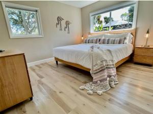 a bedroom with a bed and two windows at Sea la Vie - Beach Town Charm+Newly Renovated in Cocoa Beach