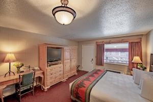 a bedroom with a bed and a desk and a television at Antler Inn in Jackson