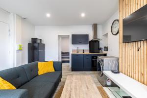 salon z niebieską kanapą i kuchnią w obiekcie Idéal couples & pro - Patio extérieur- Proche centre ville et gare - Promenade au bord de la Charente - Parking à proximité - Wifi très haut debit - Équipement premium -Netflix w mieście Angoulême