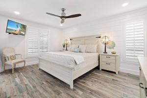 a white bedroom with a bed and a ceiling fan at Tahiti Cottage in Marco Island
