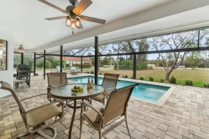a patio with a table and chairs and a pool at Tahiti Cottage in Marco Island