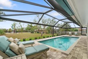 a patio with a pool and a couch and a large glass roof at Tahiti Cottage in Marco Island