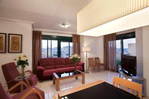 Una sala de estar con un sofá y un televisor. en Apartamentos Lomas De Campoamor, en Campoamor