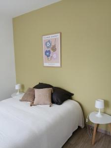 Un dormitorio con una cama blanca y un cuadro en la pared. en Au Bon ENdrOIT, en Barneville-Carteret