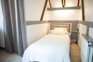 um pequeno quarto com uma cama com lençóis brancos em Hôtel-restaurant le Palais em Apt