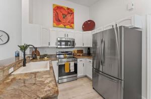 uma cozinha com um frigorífico de aço inoxidável e armários brancos em Adam's Retreat - 5 min from Beach - 2bed/2bath em Cape Canaveral