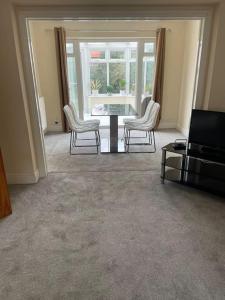 uma sala de estar com uma mesa e cadeiras e uma televisão em Lovely Detached house in lovely location em West Drayton