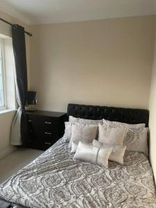 a bedroom with a bed with a black headboard and pillows at Lovely Detached house in lovely location in West Drayton