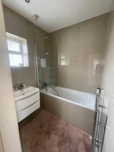 a bathroom with a white tub and a sink at Lovely Detached house in lovely location in West Drayton