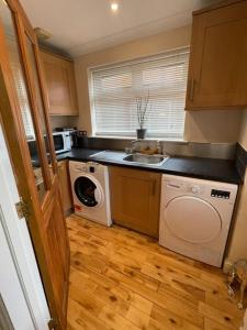 uma cozinha com um lavatório e uma máquina de lavar roupa em Lovely Detached house in lovely location em West Drayton