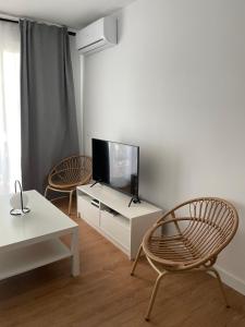 Apartamento Colina B 19. في قرطبة: غرفة معيشة مع كرسيين وتلفزيون بشاشة مسطحة