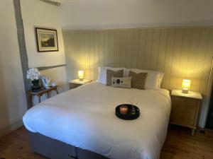 a large white bed with a black hat on it at Woolpack Inn in Canterbury