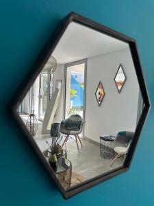 un miroir reflétant le salon avec un canapé et des chaises dans l'établissement Hotel La Voile, à Bormes-les-Mimosas