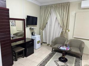 Al Farhan Hotel Suites Al siteen في الجبيل: غرفة معيشة فيها تلفزيون وطاولة وكراسي