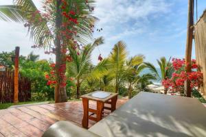 a patio with a table and red flowers and palm trees at Marmot Hill Apartment, loft for 2, Las Pocitas in Máncora