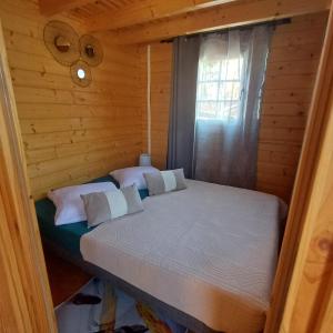 Cama en habitación de madera con ventana en Le Chalet d'EVOA en Étang-Salé
