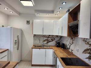 cocina con armarios blancos y encimera de madera en Apartament z widokiem, en Zgorzelec