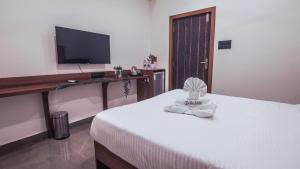 a bedroom with a bed with a desk and a television at Radhe Suites in Hyderabad