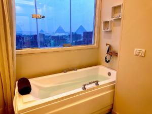 a bath tub in a bathroom with a window at pyramids guest house in Cairo