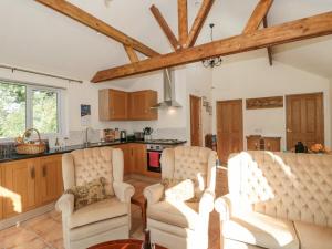 uma sala de estar com duas cadeiras e uma cozinha em Lapwing Lodge em Cullompton
