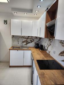 a kitchen with white cabinets and a wooden counter top at Apartament z widokiem in Zgorzelec